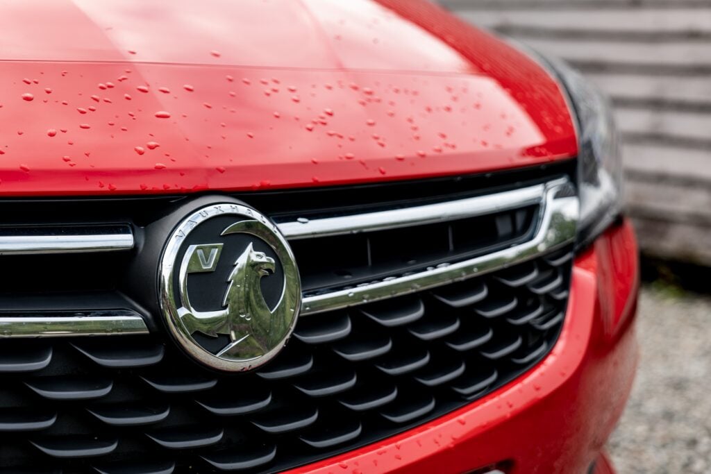 The frontal part of a red Vauxhall Astra hatchback car with a grill and badge of this auto maker